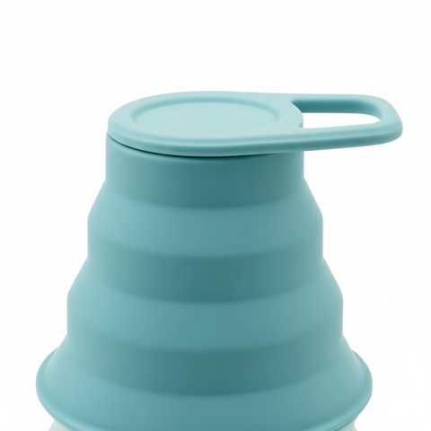 Close-up of the mint cap with integrated carry loop and silicone ridges of the collapsible water bottle on pure white background